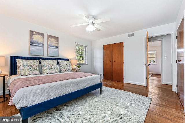 bedroom featuring visible vents, baseboards, wood finished floors, a closet, and a ceiling fan