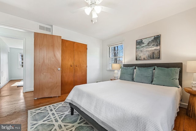 bedroom featuring visible vents, baseboards, ceiling fan, wood finished floors, and a closet