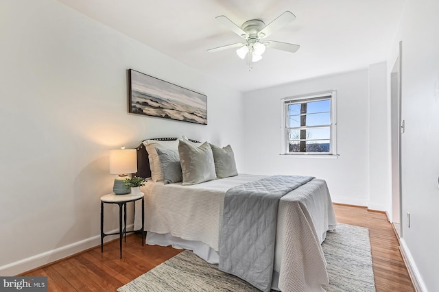 bedroom featuring baseboards, wood finished floors, and a ceiling fan