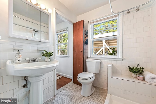 bathroom featuring tile patterned floors, toilet, and tile walls