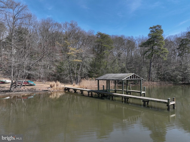 view of dock with a forest view and a water view