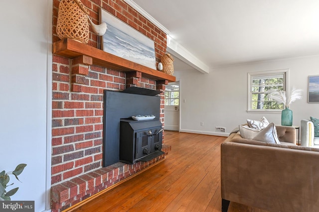 living area featuring baseboards, a healthy amount of sunlight, hardwood / wood-style floors, and a wood stove