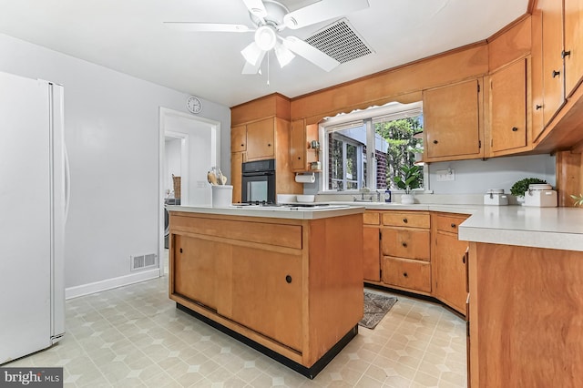 kitchen featuring oven, visible vents, a center island, freestanding refrigerator, and light countertops