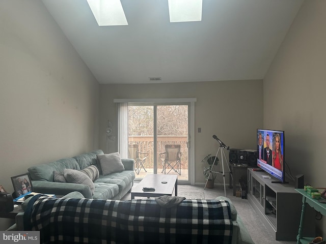 carpeted living room with visible vents and vaulted ceiling with skylight