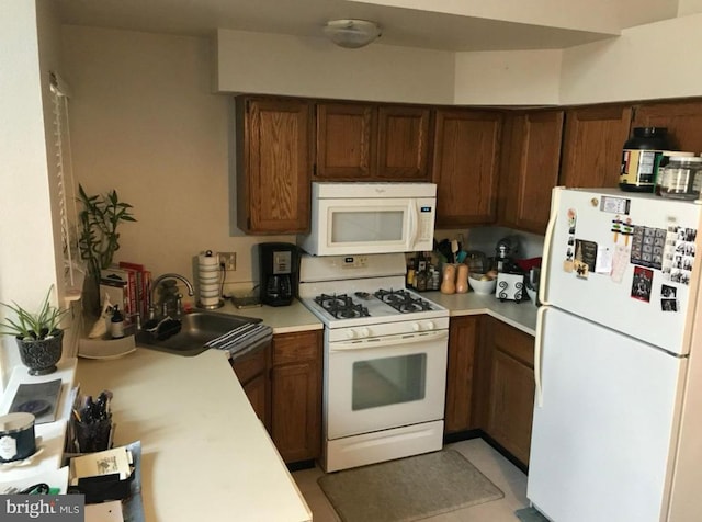 kitchen with white appliances, light countertops, and a sink