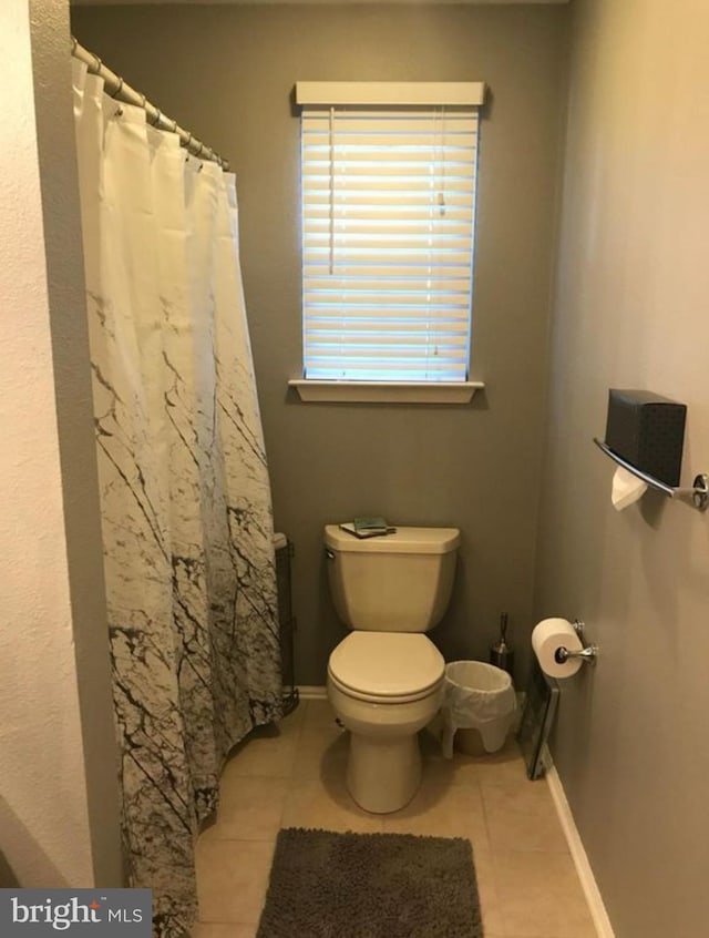 bathroom featuring baseboards, toilet, and tile patterned flooring