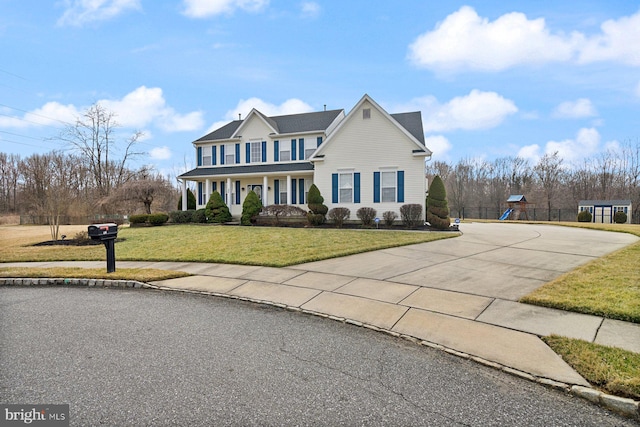 view of front of home with a front lawn, a playground, and concrete driveway