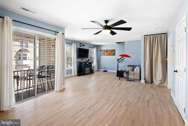 living area featuring visible vents, baseboards, wood finished floors, and a ceiling fan