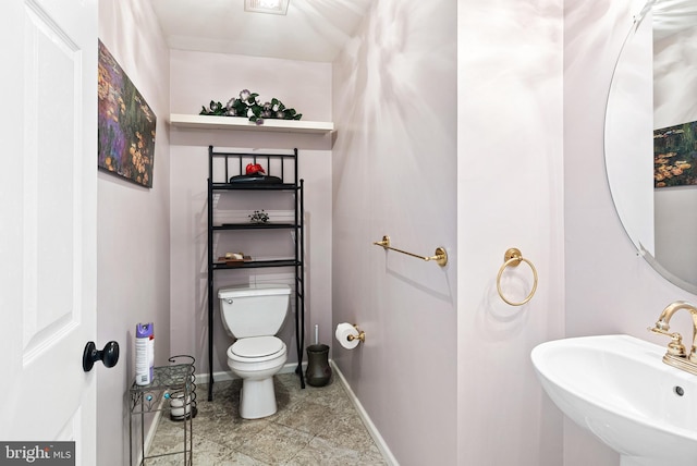 bathroom featuring toilet, baseboards, and a sink