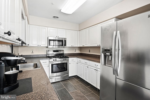 kitchen with white cabinetry, dark countertops, visible vents, and appliances with stainless steel finishes