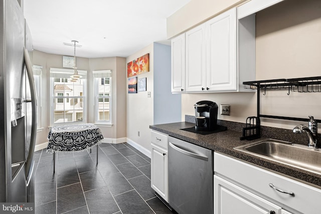 kitchen featuring a sink, stainless steel appliances, white cabinets, pendant lighting, and dark countertops