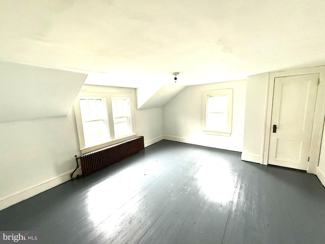 bonus room with dark wood-style flooring, radiator heating unit, vaulted ceiling, and a healthy amount of sunlight