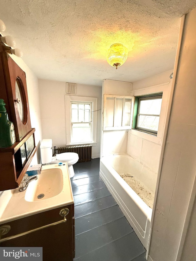 full bathroom with radiator heating unit, a wealth of natural light, a tub, and toilet
