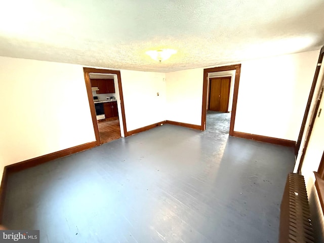 spare room featuring baseboards and a textured ceiling