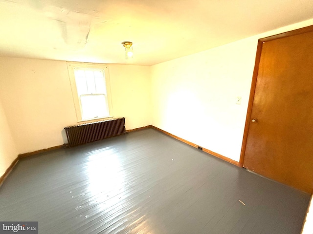 unfurnished room with radiator, wood finished floors, and baseboards