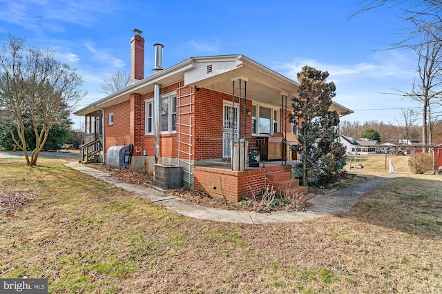 view of side of property featuring brick siding, a porch, central AC unit, a lawn, and a chimney