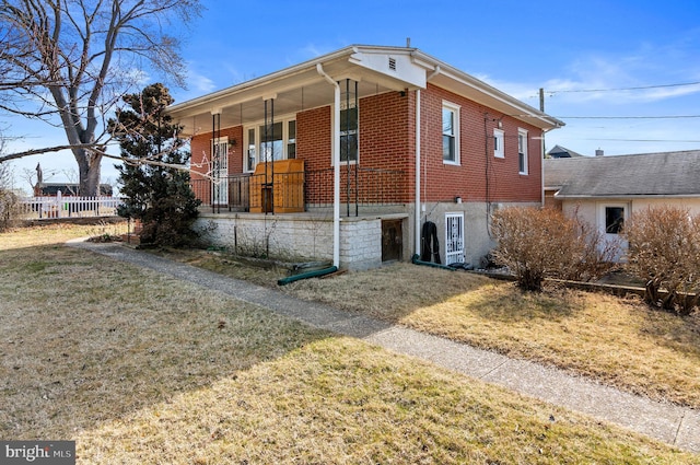 view of front of property featuring brick siding, a porch, a front yard, and fence