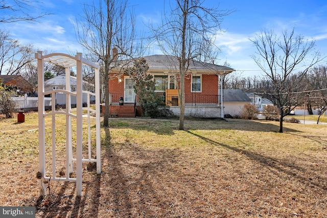 bungalow with a front lawn, fence, brick siding, and a chimney