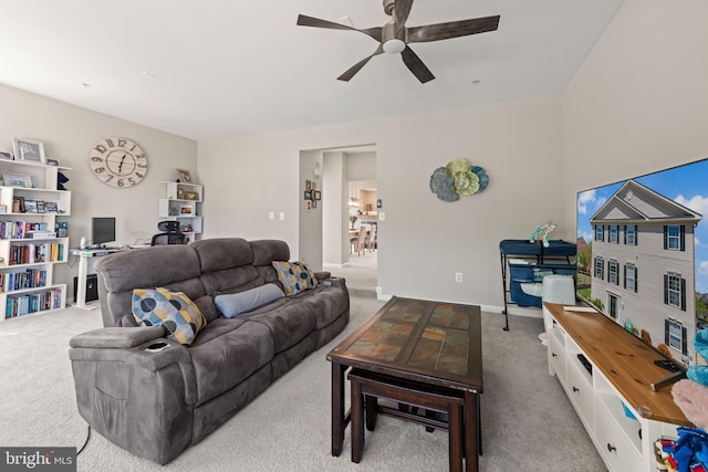 living area featuring baseboards, a ceiling fan, and carpet flooring