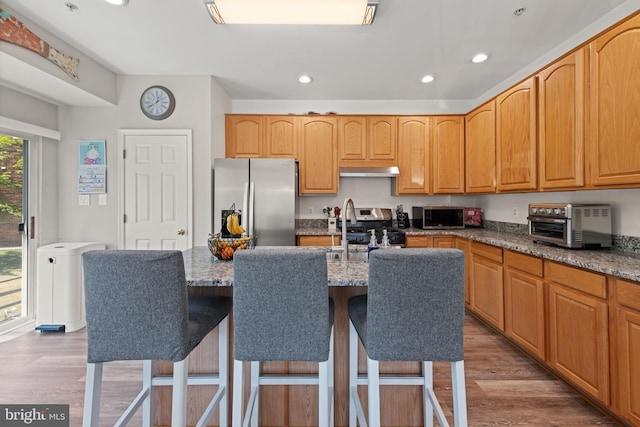 kitchen with recessed lighting, appliances with stainless steel finishes, stone counters, and wood finished floors