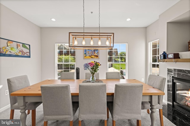 dining space with baseboards, a high end fireplace, and recessed lighting