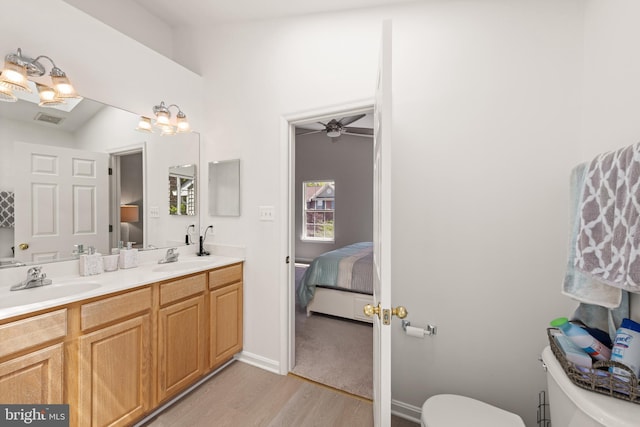 ensuite bathroom with ensuite bathroom, a sink, wood finished floors, and toilet