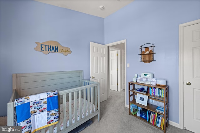 carpeted bedroom featuring baseboards and a nursery area