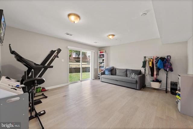 workout room featuring baseboards, light wood finished floors, and visible vents