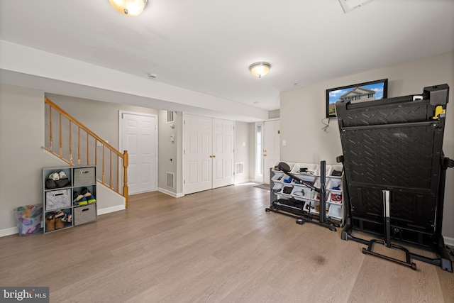 exercise area featuring baseboards, visible vents, and wood finished floors