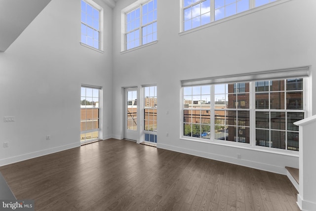 unfurnished living room featuring baseboards and dark wood-type flooring