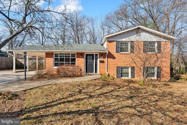 tri-level home with a carport, concrete driveway, brick siding, and fence