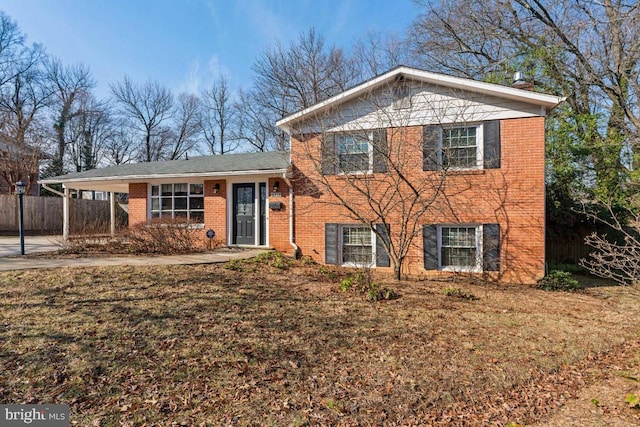 tri-level home with an attached carport, fence, brick siding, and driveway