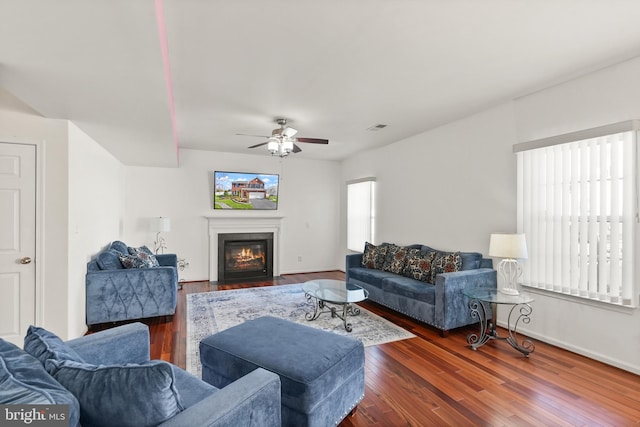 living room with plenty of natural light, dark wood-style floors, visible vents, and ceiling fan