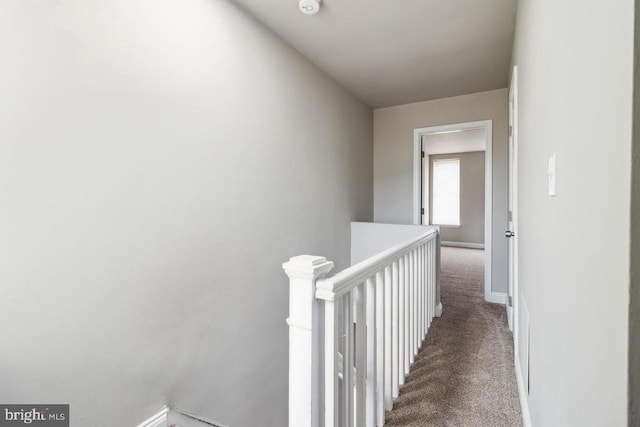 hall featuring carpet flooring, an upstairs landing, and baseboards