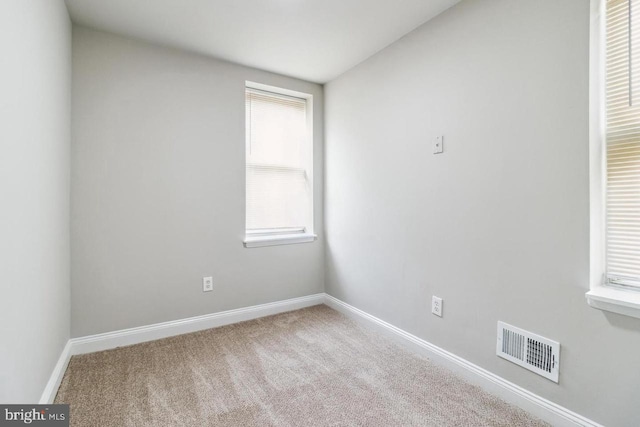 carpeted spare room featuring visible vents and baseboards