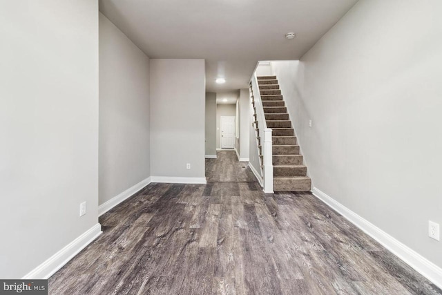 unfurnished living room with stairway, baseboards, and wood finished floors