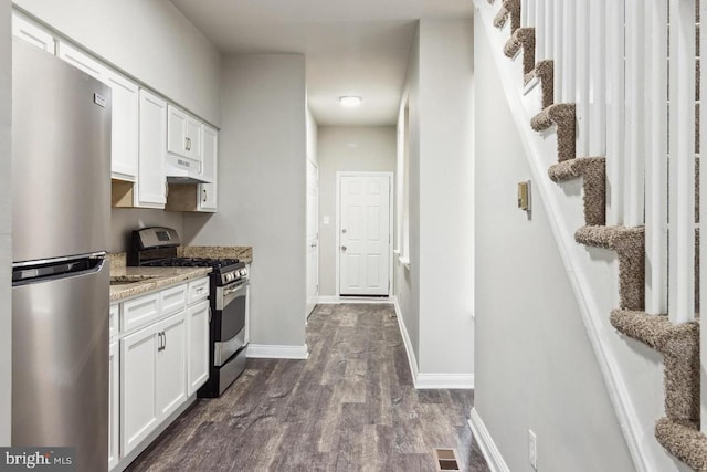 kitchen featuring dark wood finished floors, under cabinet range hood, white cabinets, and appliances with stainless steel finishes