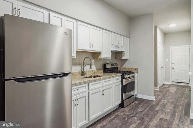 kitchen with under cabinet range hood, appliances with stainless steel finishes, a sink, and white cabinetry