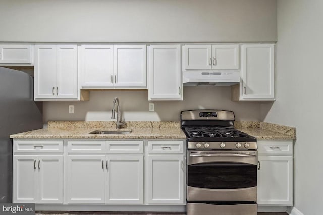 kitchen with under cabinet range hood, light stone counters, appliances with stainless steel finishes, white cabinets, and a sink