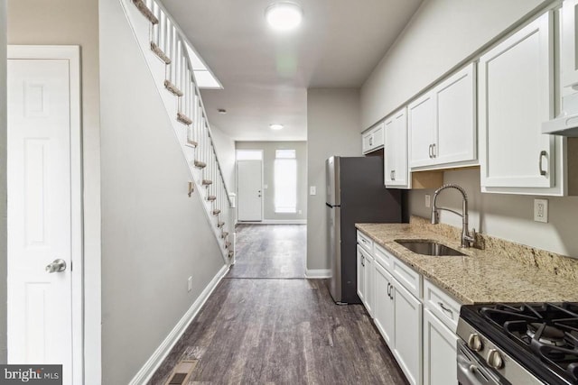 kitchen with dark wood-type flooring, baseboards, stainless steel appliances, white cabinetry, and a sink