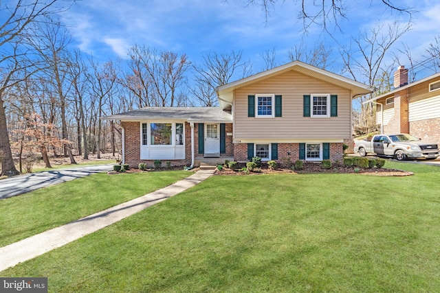 split level home featuring a front lawn and brick siding