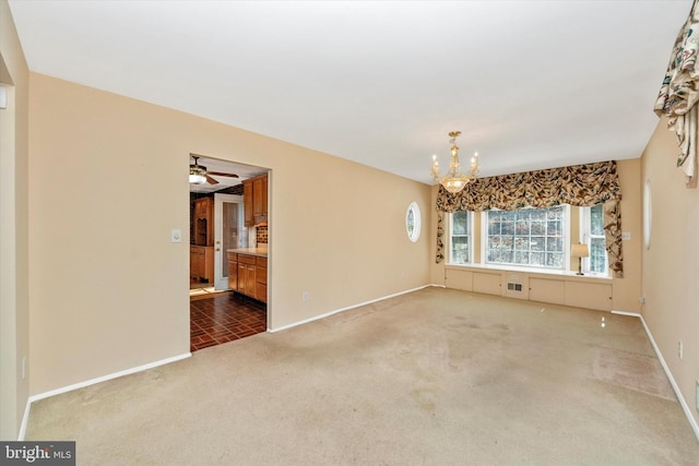 spare room with baseboards, carpet, and ceiling fan with notable chandelier