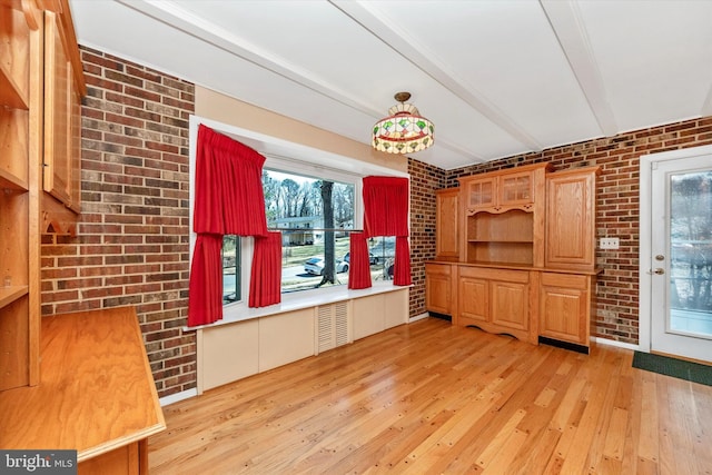 unfurnished living room featuring a wealth of natural light, beamed ceiling, and brick wall