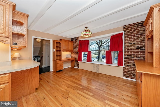 kitchen with brick wall, built in study area, open shelves, beam ceiling, and light wood-type flooring