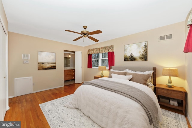 bedroom featuring visible vents, connected bathroom, baseboards, wood finished floors, and a ceiling fan