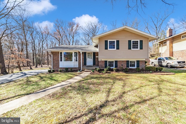 tri-level home featuring a front lawn and brick siding