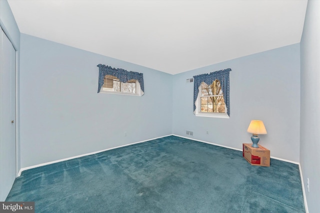 carpeted empty room featuring baseboards and visible vents