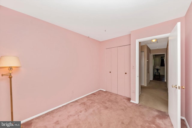 unfurnished bedroom featuring light colored carpet, a closet, and baseboards