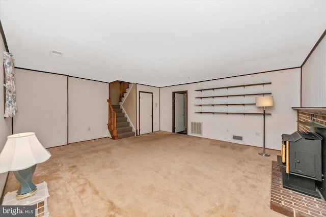 below grade area with visible vents, carpet flooring, stairs, and a wood stove