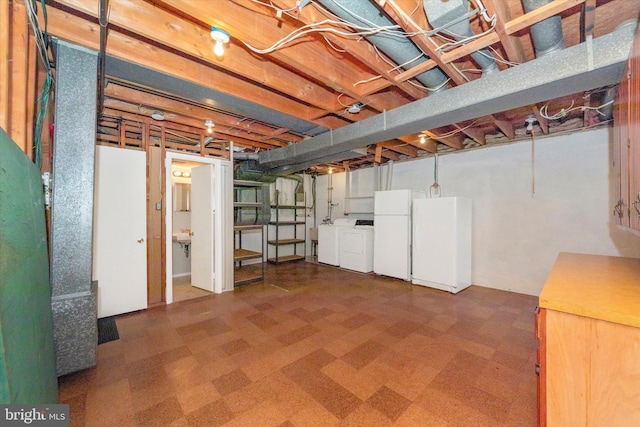 unfinished basement with tile patterned floors, separate washer and dryer, and freestanding refrigerator